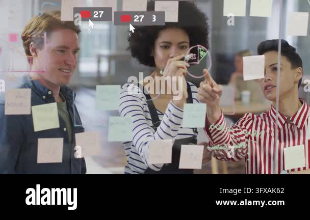 Team sketching pie chart on glass placing notes as social icons ...