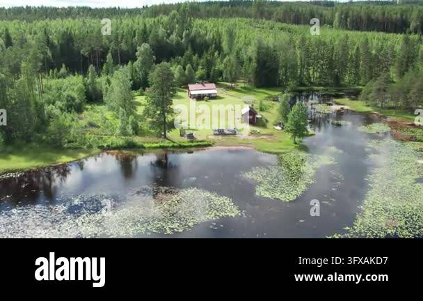 A Lake Rannsjon bay with lily pads, a small island with a red house ...