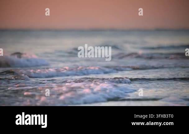 Smooth Color Sunset Waves gently roll onto the shore during sunset. Soft colors in the sky ...