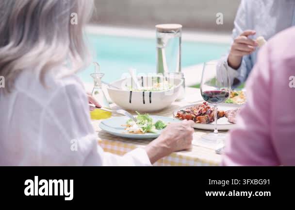 Group of elderly friends gathered around a table for a cheerful outdoor ...