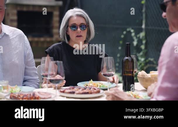 Group of mature friends having lunch together in a garden. They are ...