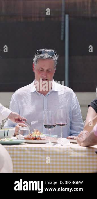 Middle aged gray haired man smiling and chatting with friends during an ...