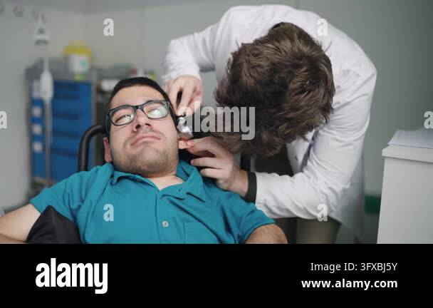 Otoscpy Young man with a disability undergoing a routine otoscopy exam by a ...