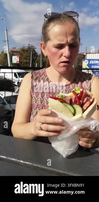 Woman actively fights off annoying wasp from sandwich wrap outdoors in ...