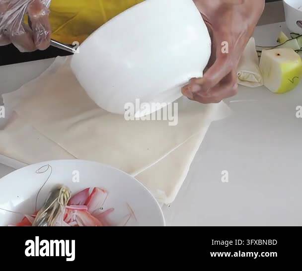 Close Up Hand making fresh spring rolls, rolling delicate translucent ...
