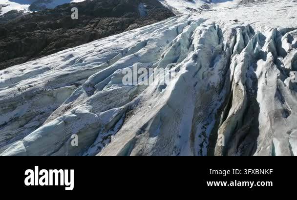 Aerial drone footage slowly tracking over a vast, icy glacier with deep ...