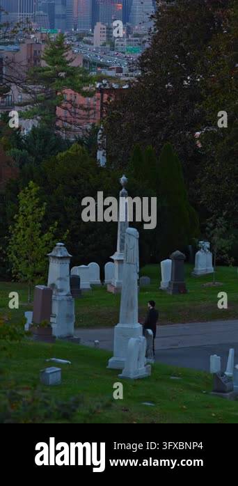 Cemetery monuments overlook Brooklyn buildings and highway traffic. Two ...