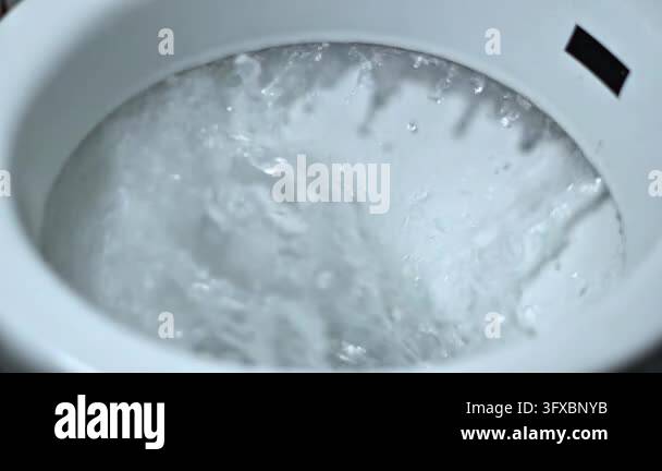 Close-up view of water swirling and flushing inside a clean white ...