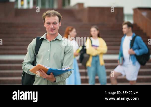 Portrait of a happy male student holding folders and a backpack on ...
