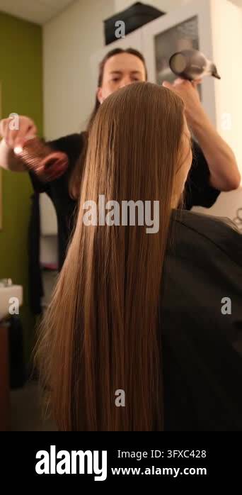 Professional hairdresser drying and styling a clients beautiful long ...