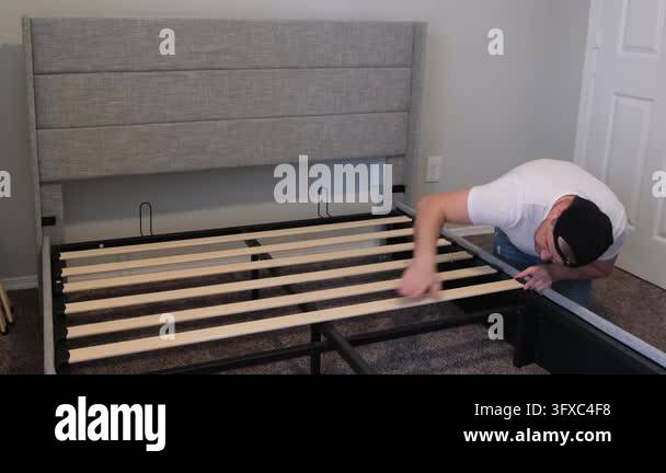 Diligent man assembling a new bed frame, carefully placing the wooden ...
