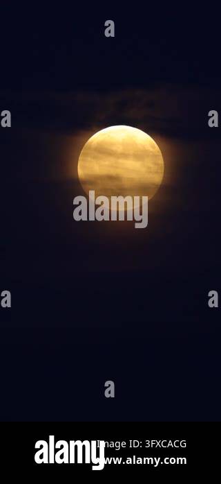 4k Moon Rising Full glowing moon rising through soft clouds in dark blue evening sky ...