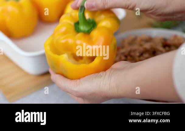 Is There Healthy Rice Woman spoons rice and minced meat filling into hollowed yellow bell ...