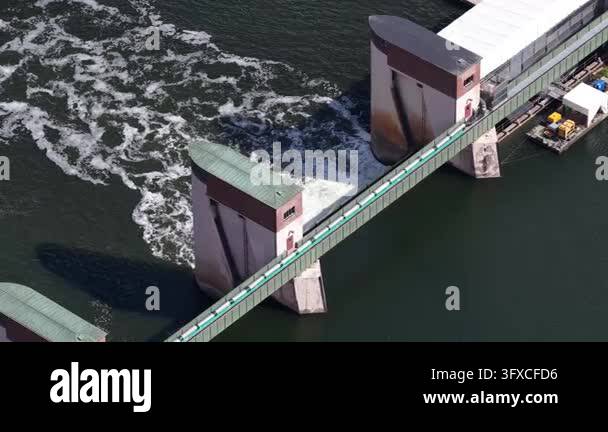 Water rushing and churning over a large weir structure, with control ...