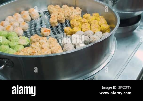 Assorted colorful dim sum dumplings steam in large metal steamer at ...