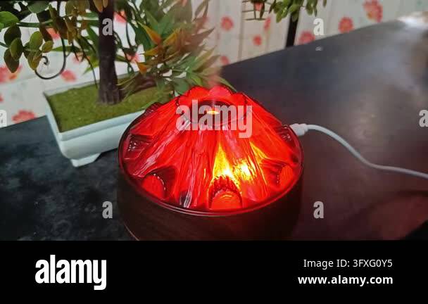 Valcano Red Volcano mist diffuser glowing red beside faux bonsai plant with USB ...