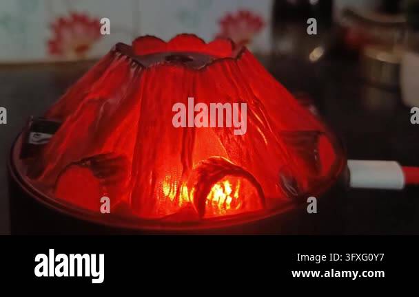 Valcano Red Glowing red volcano shaped diffuser emitting mist on dark wooden desk ...