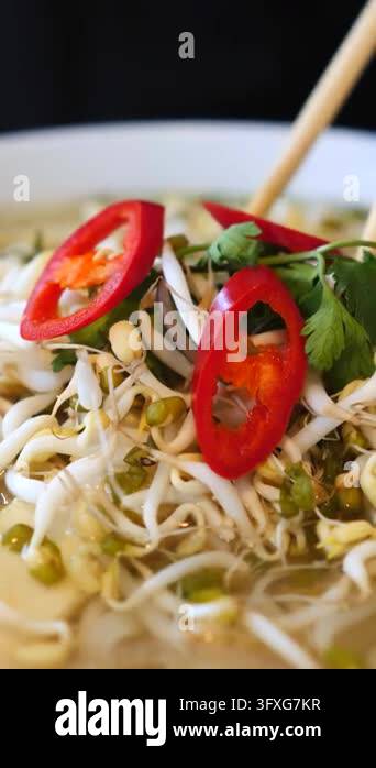 Fat Rice Needoles Rice noodles rise from steaming bowl as chopsticks pull them upward ...