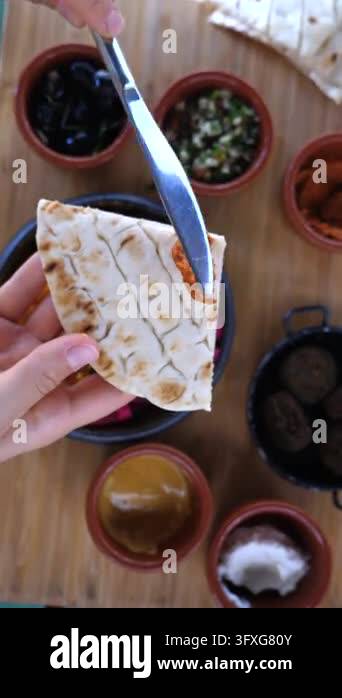 Spice Building Hand spreads cream on flatbread and adds spice, building savory wrap in ...