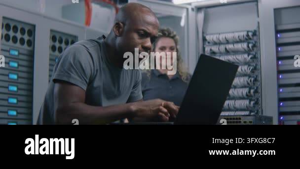 IT Specialist Analyzing Server Performance Metrics on Laptop While ...