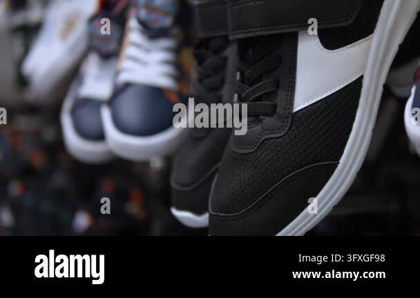 Black sneakers with white panels dangle in shop display, gently moving ...