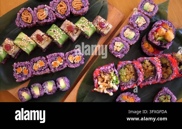 Yo Sushi Rice Assorted sushi rolls rest on black slate and wood trays in vibrant food ...
