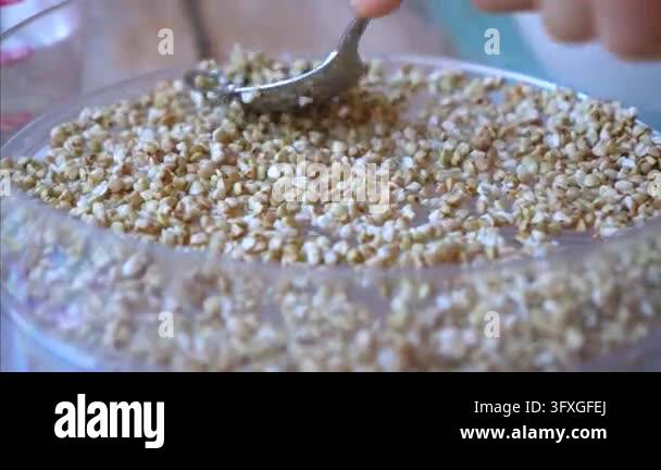 Finger/hand Framing Hand stirs coarse grain in glass bowl with spoon. Close up food ...