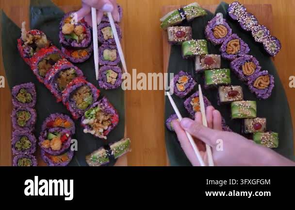 Yo Sushi Rice Colorful sushi rolls are arranged on dark platters while hands lift ...