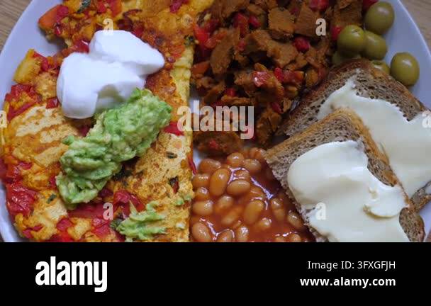 Hearty breakfast plate features omelet, baked beans, bread with cheese ...
