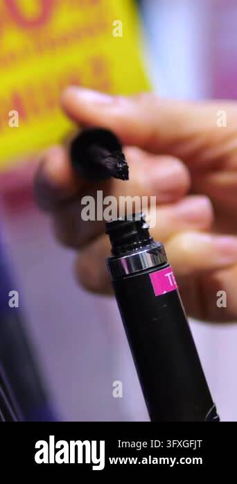 Hand opens and closes black mascara tube, lifting brush applicator to ...