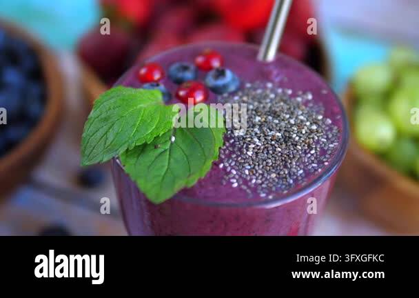 Berry smoothie topped with chia seeds sits in glass with mint leaves ...