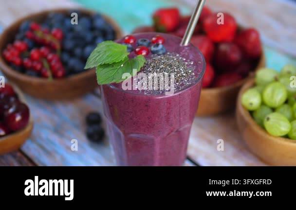 Purple berry smoothie stands among bowls of blueberries, grapes ...
