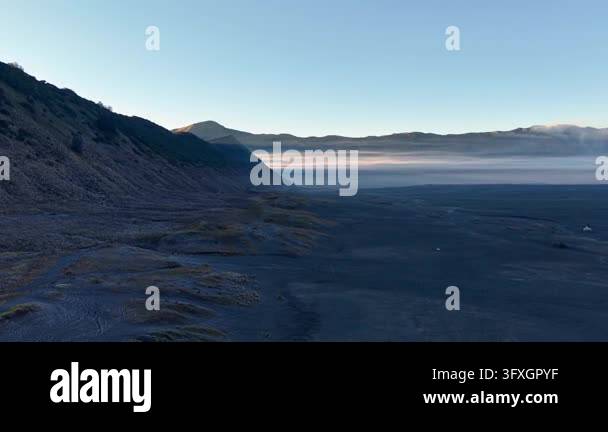 Dramatic volcanic landscape bathed in soft dawn light. Misty valley ...