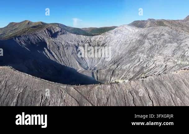Dramatic sunrise lit volcanic crater rim with hikers, steam vents ...
