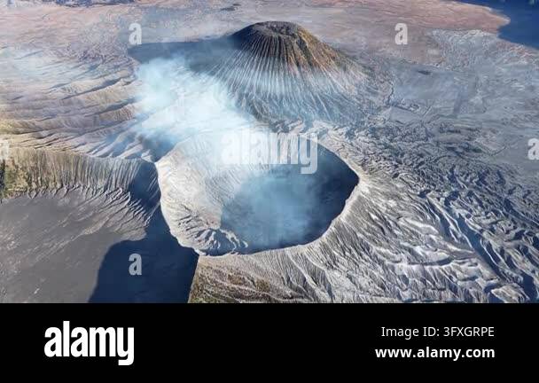 Volcano Smoking Volcano exhales mist from its crater. Rugged terrain surrounds the ...