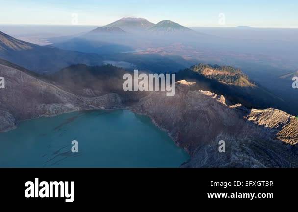 Volcanic View Aerial view of volcanic landscape with turquoise lake. Smoke drifts ...