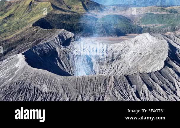 Volcano Smoking Volcano spews smoke from its crater. Rugged slopes surround the smoking ...