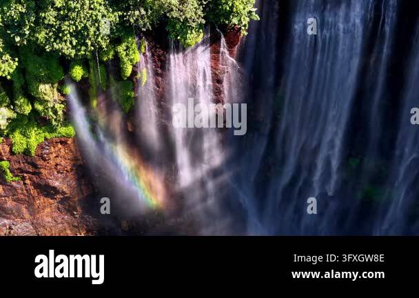 Waterfalls cascade over mossy rocks, creating mist at Tumpak Sewu Stock ...