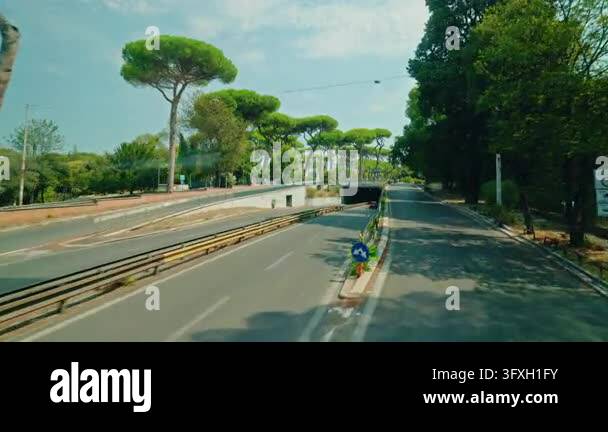 Rome, Italy August 20, 2026: A moving bus passes a tree-lined road ...