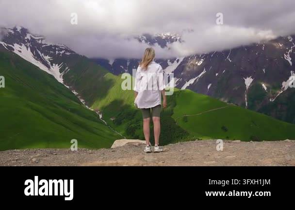 Snowing In Georgia Young woman standing on top of a mountain with her hands raised ...