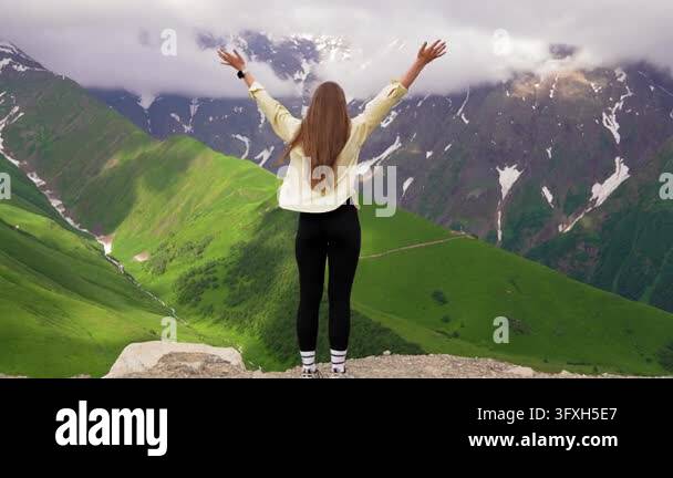 Snowing In Georgia Back view of carefree young woman standing on the edge of a mountain ...
