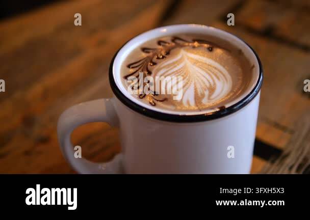 Latte art rests atop cappuccino in white ceramic cup, with feathered ...