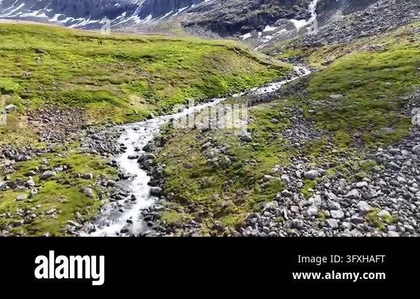 Rocky Stream Vector Aerial drone footage flying over a rocky, green mountain valley with a ...