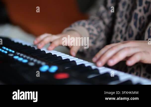 Child presses electronic keyboard keys with both hands during music ...