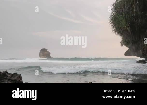 Prominence 4k Ocean waves rolling and breaking against a rocky shore, framed by ...