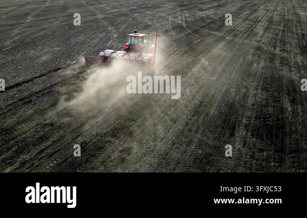 Aerial drone view of a tractor sowing seeds in a large agricultural ...