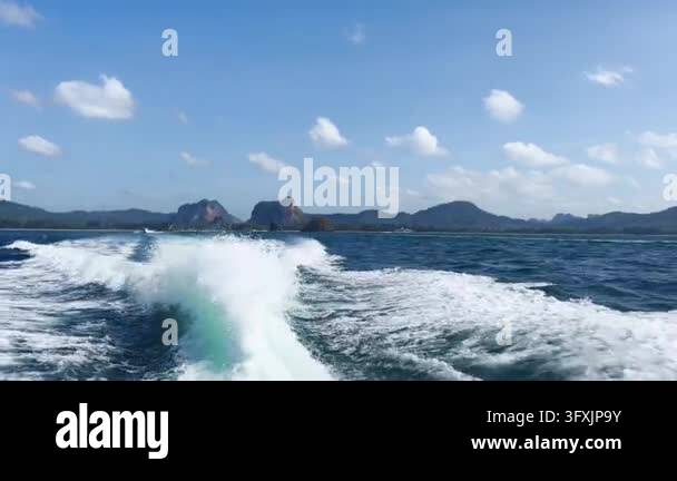 Handheld tracking shot from speedboat stern, white wake churning over ...