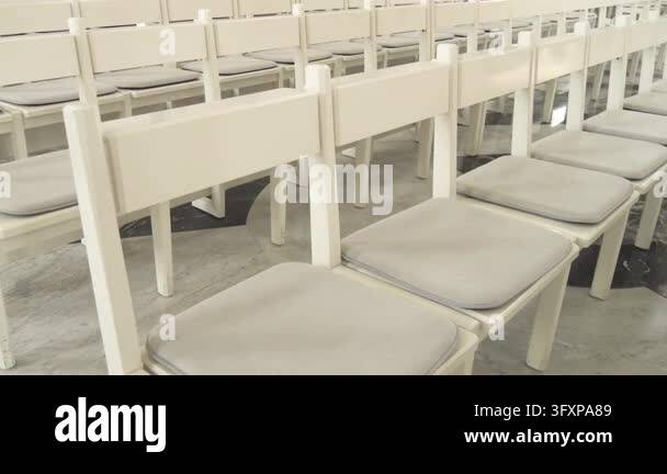Traditional religious interior featuring many white wooden pews ...