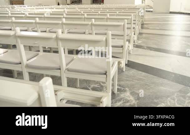 Repeating rows of white wooden church pews create a geometric pattern ...