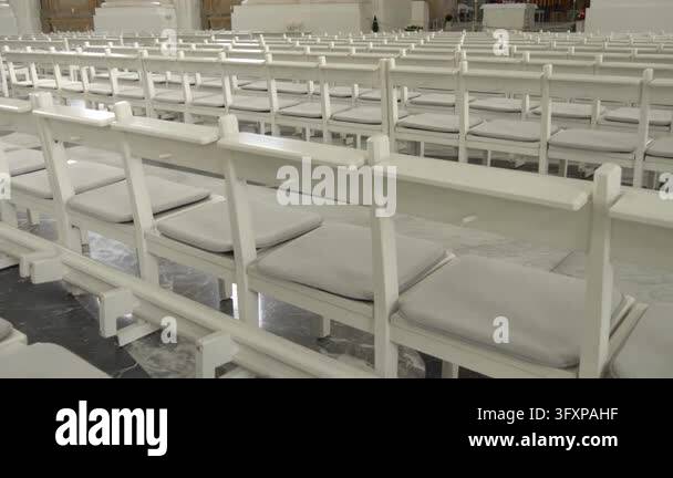 Perspective view across numerous empty church pews arranged in parallel ...